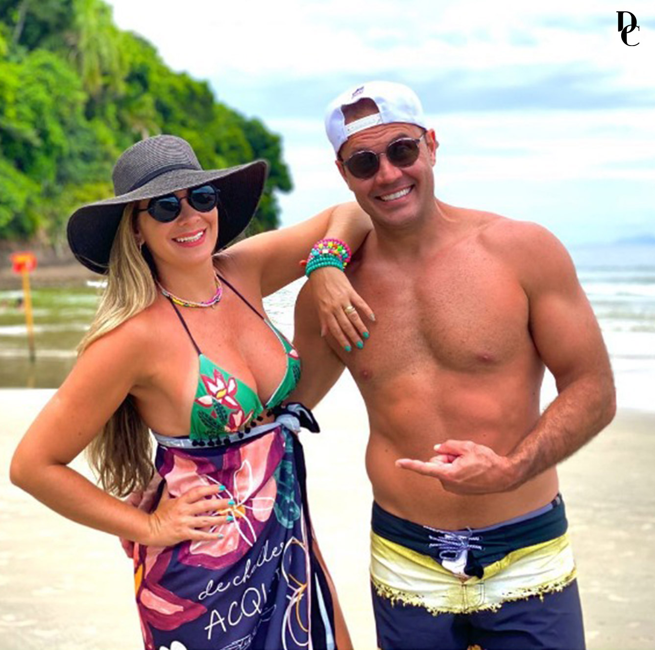 casal alegre na praia vestindo de chelles