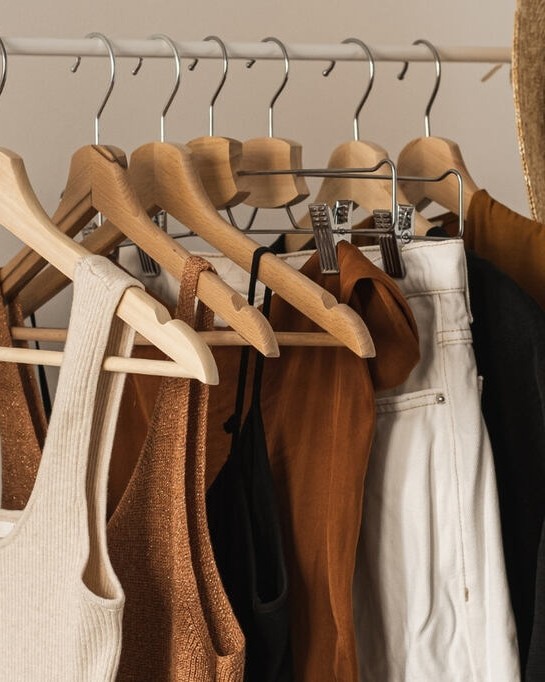 Peças neutras e coordenáveis, ideiais para Guarda-roupa cápsula feminino penduradas em uma arara de roupas