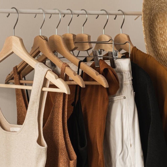 Peças neutras e coordenáveis, ideiais para Guarda-roupa cápsula feminino penduradas em uma arara de roupas