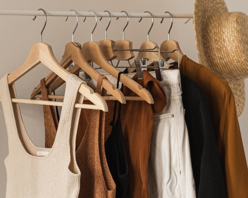 Peças neutras e coordenáveis, ideiais para Guarda-roupa cápsula feminino penduradas em uma arara de roupas