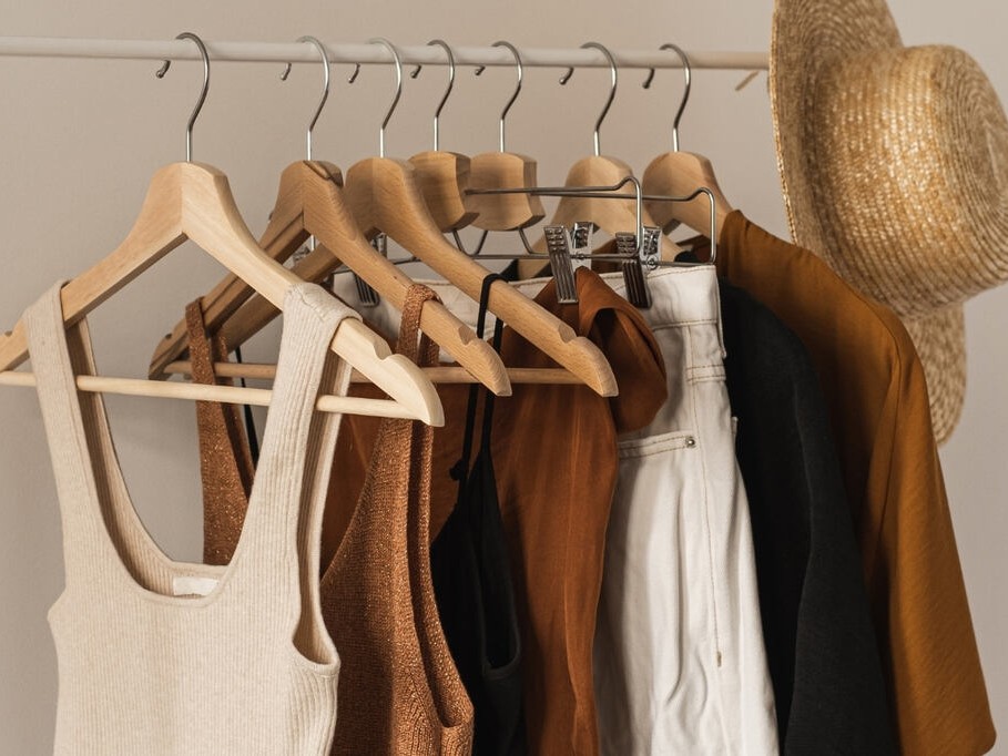 Peças neutras e coordenáveis, ideiais para Guarda-roupa cápsula feminino penduradas em uma arara de roupas