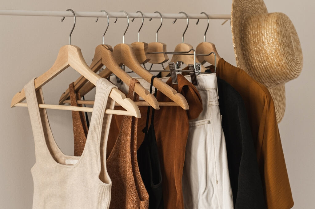 Peças neutras e coordenáveis, ideiais para Guarda-roupa cápsula feminino penduradas em uma arara de roupas