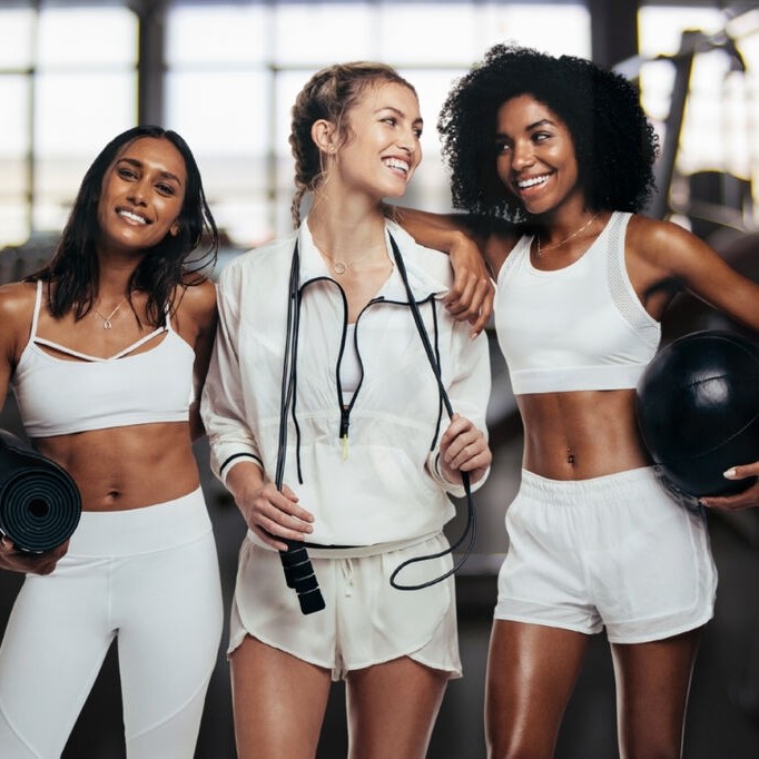 Mulheres usando look fitness feminino na cor branca para academia, com peças confortáveis e funcionais